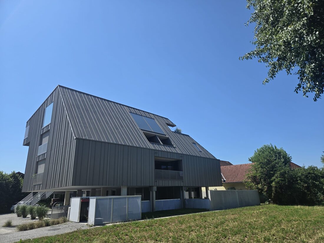 Modernes Mehrfamilienhaus mit dunkler Stehfalz-Metallfassade